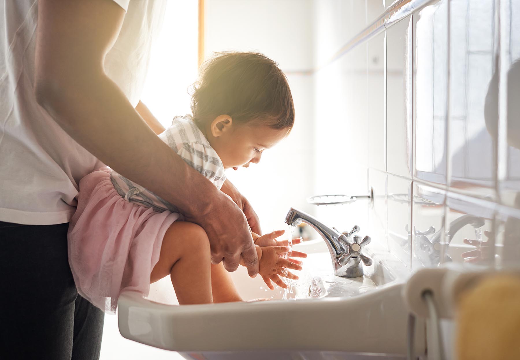 Toddler washing hands at sink